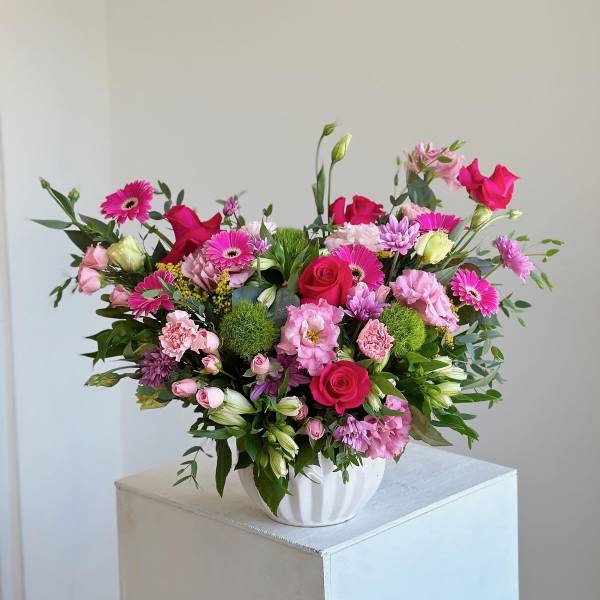 Pink and magenta mixed flower arrangement in a white vase