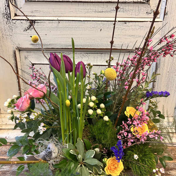 Mixed floral arrangement with pink and yellow roses in a low container