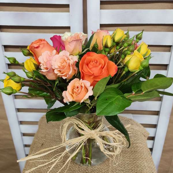 Bouquet of orange, peach, and yellow roses in a glass vase