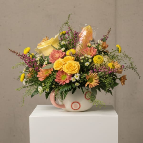 Mixed bouquet in a white mug-style vase with yellow and pink flowers