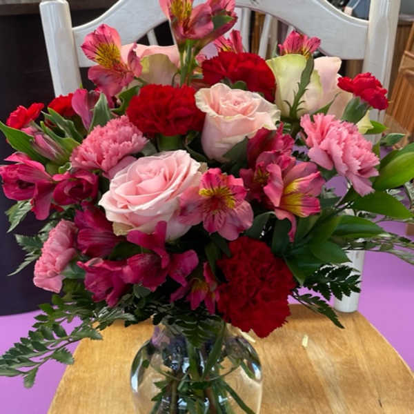Mixed bouquet of pink and red flowers in a clear glass vase