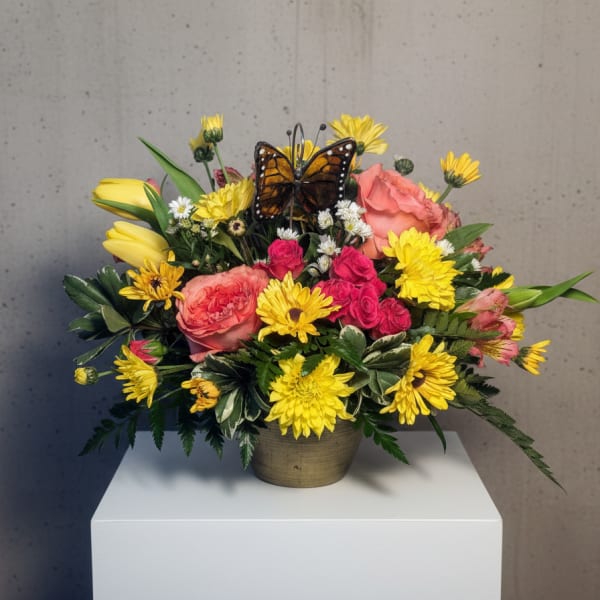 Bright mixed bouquet in a small vase with a butterfly accent