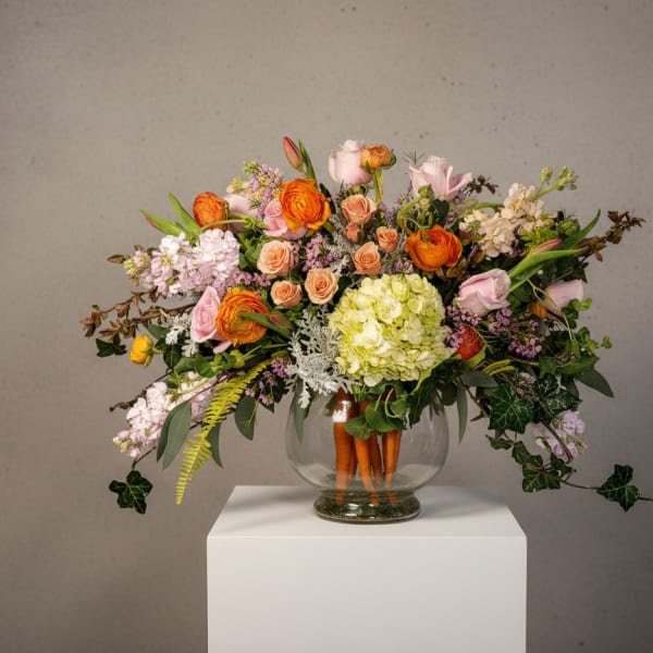 Mixed bouquet in a clear glass vase with orange, pink, and cream blooms