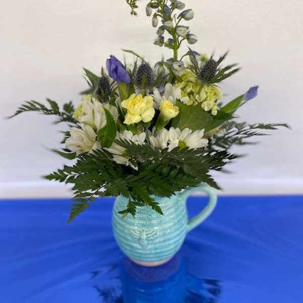 Blue and white flower arrangement in a light blue ceramic pitcher