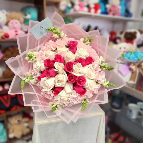 Bouquet of pink and white roses wrapped in pale pink paper