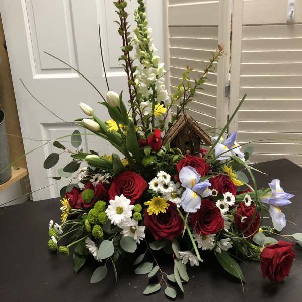 Mixed bouquet with red roses, white tulips, and daisies around a birdhouse