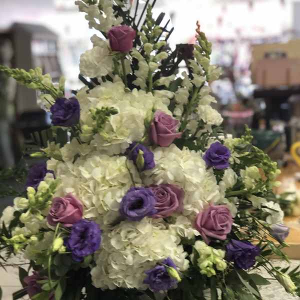 Tall floral arrangement with white hydrangeas and purple and pink roses