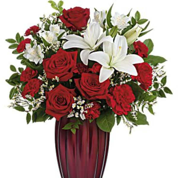 Red roses and white lilies arranged in a tall burgundy vase