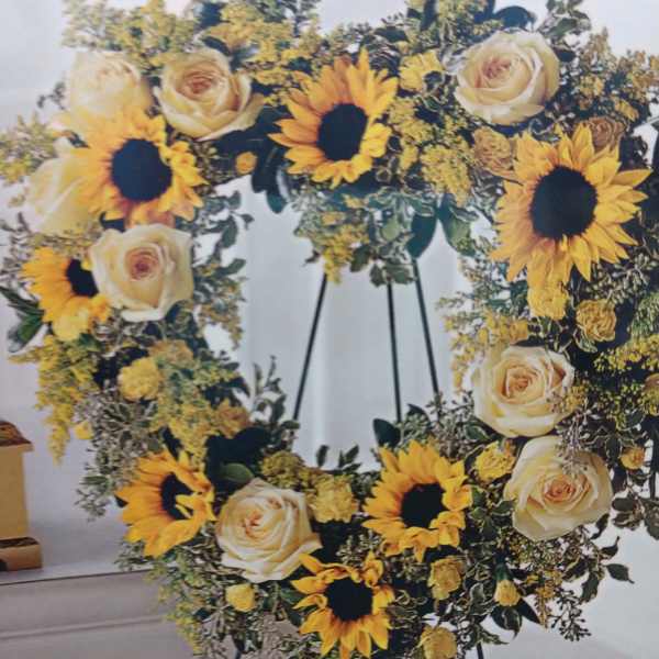 Heart-shaped floral wreath with sunflowers and cream roses on an easel