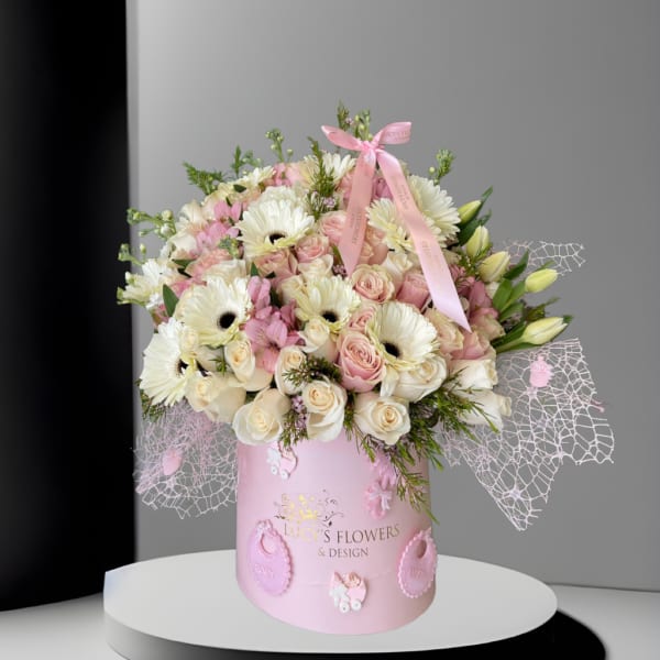 Pink and white bouquet in a pink hatbox with baby-themed decorations