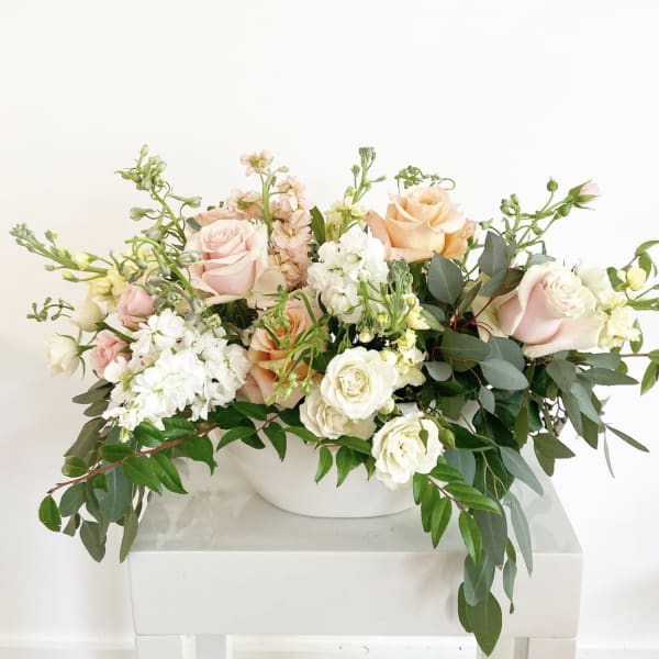 Arrangement of blush and cream roses in a white bowl vase