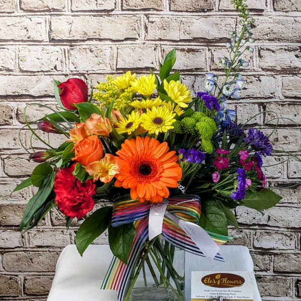 Colorful mixed bouquet in a glass vase with a striped ribbon