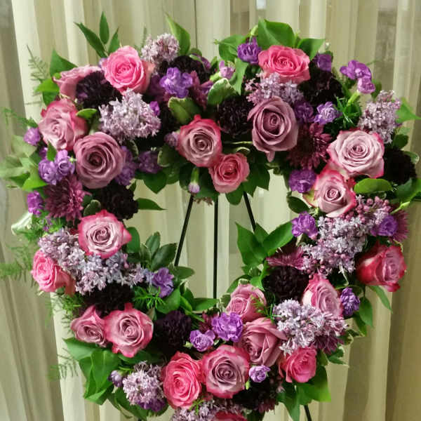 Heart-shaped floral wreath of pink and purple roses on a stand