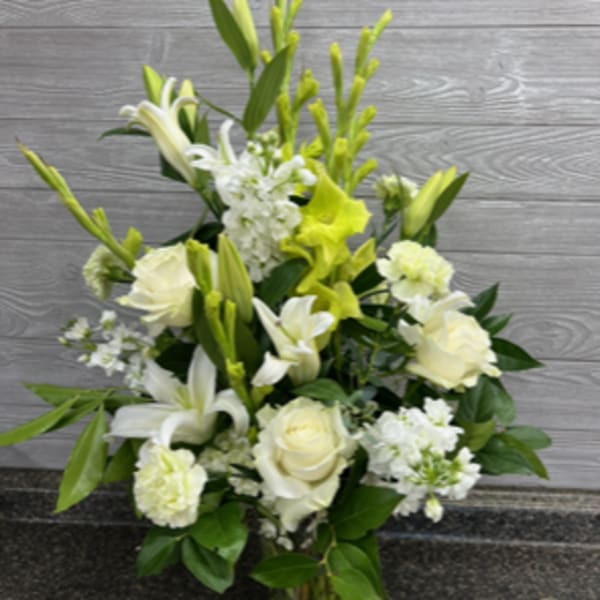 White and pale yellow floral arrangement in a clear glass vase