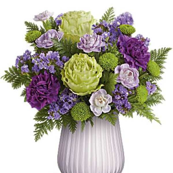 Purple and green floral arrangement in a ribbed glass vase