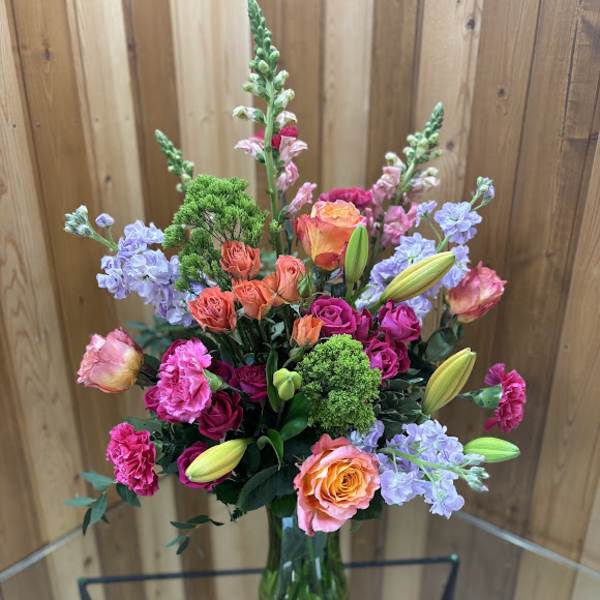 Mixed bouquet in a glass vase with roses, lilies, and pink blooms