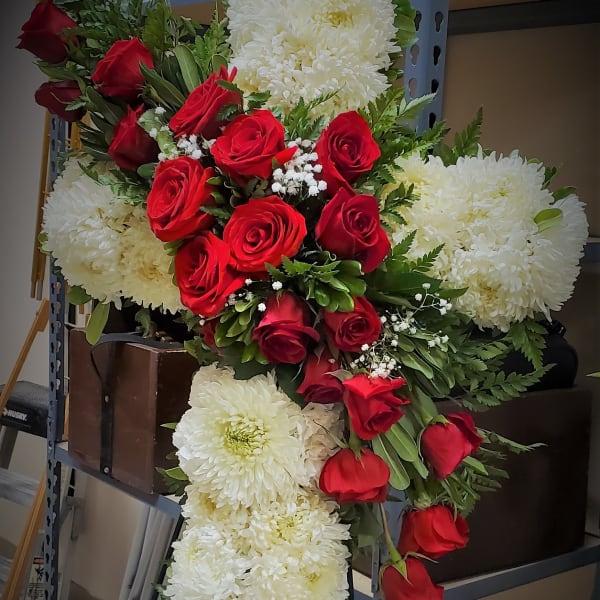 Cross-shaped floral arrangement of red roses and white chrysanthemums