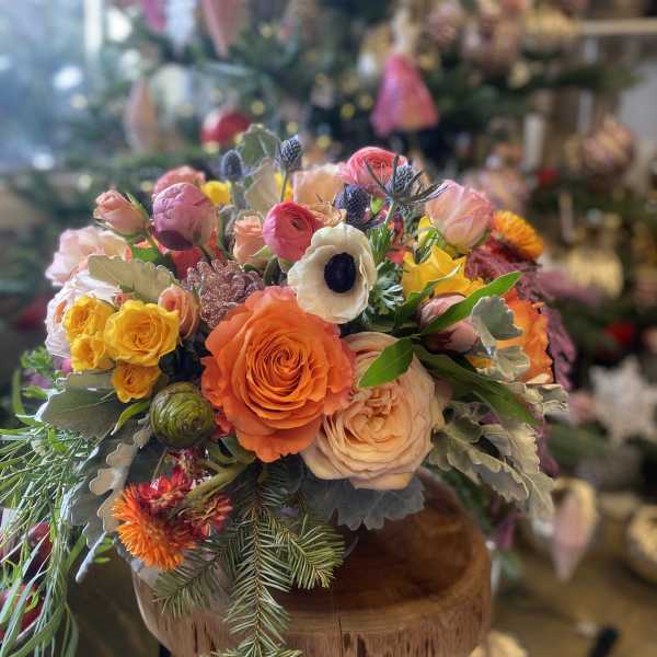 Colorful bouquet of roses and ranunculus in a wooden container