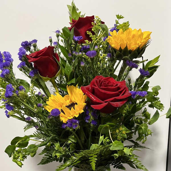 Bouquet of red roses and yellow sunflowers in a clear glass vase