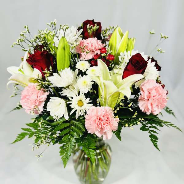 Bouquet of lilies, roses, carnations, and daisies in a glass vase