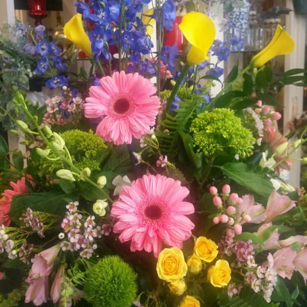 Mixed bouquet with pink gerberas, blue delphinium, yellow calla lilies, and roses