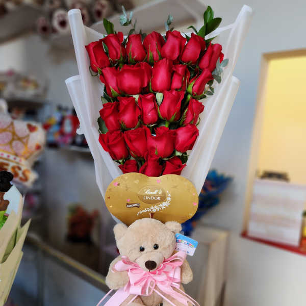 Bouquet of red roses with a teddy bear and chocolate gift topper