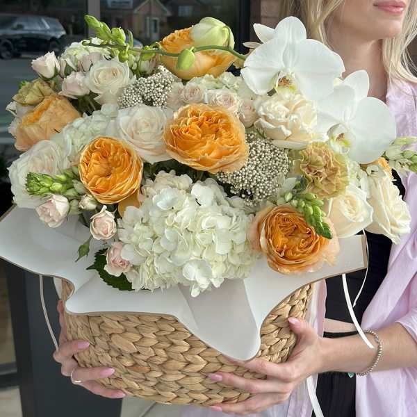 Bouquet of white and peach flowers in a woven basket