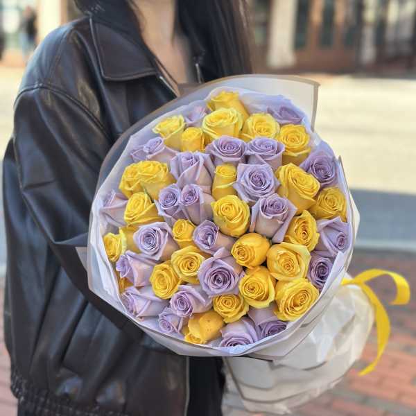 Bouquet of yellow and lavender roses wrapped in white paper
