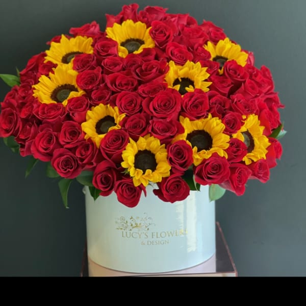 Red roses and yellow sunflowers in a white hat box