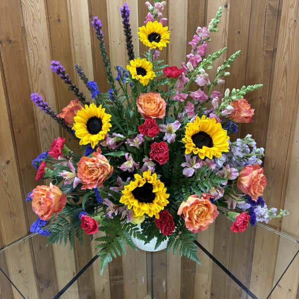 Mixed bouquet with sunflowers, roses, and snapdragons in a white vase
