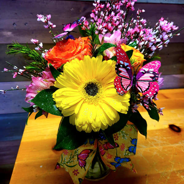 Bright mixed bouquet with a yellow gerbera and orange rose in a butterfly-decorated vase