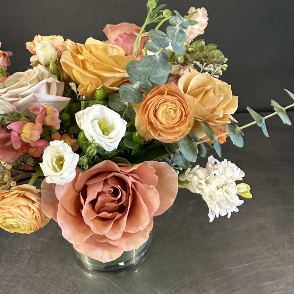 Mixed bouquet of peach, white, and yellow flowers in a glass vase
