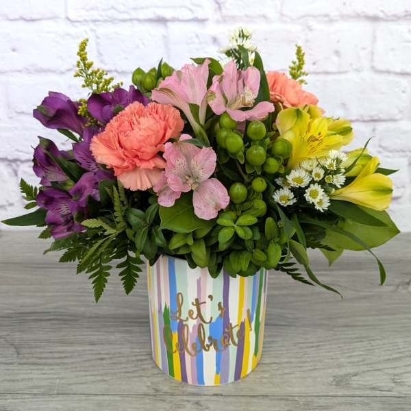 Colorful mixed flower arrangement in a striped "Let's Celebrate" container