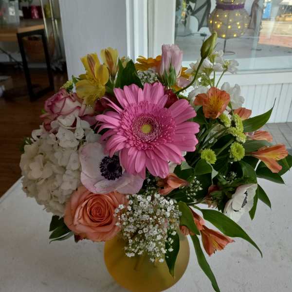 Mixed bouquet with pink gerbera, roses, hydrangea, and alstroemeria in a yellow vase