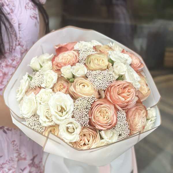 Bouquet of peach and white roses wrapped in pale paper