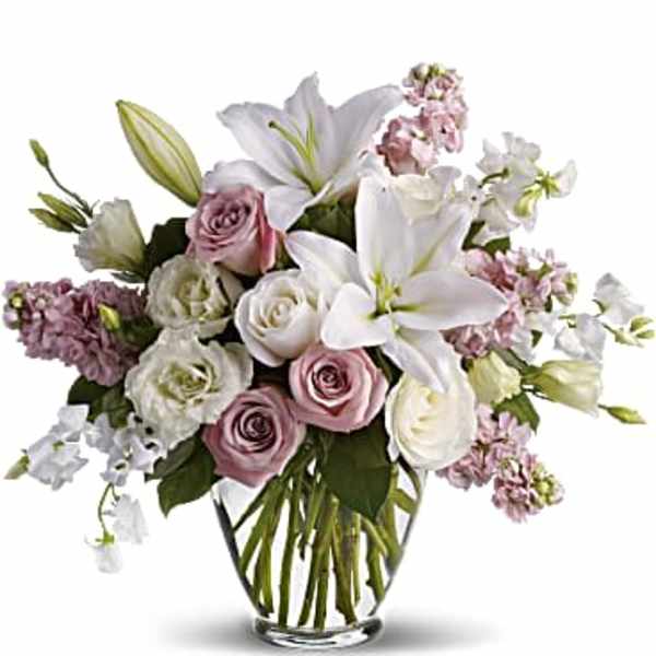 Bouquet of white lilies and pink roses in a clear glass vase