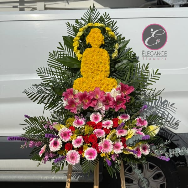 Standing floral tribute with yellow, pink, and red flowers on an easel