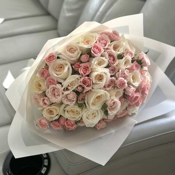 Bouquet of pink and cream roses wrapped in white paper