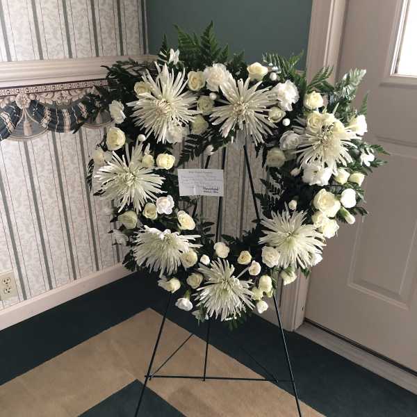 White floral wreath on a black easel stand