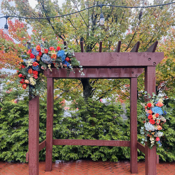 Floral arrangements draped over a wooden arch outdoors