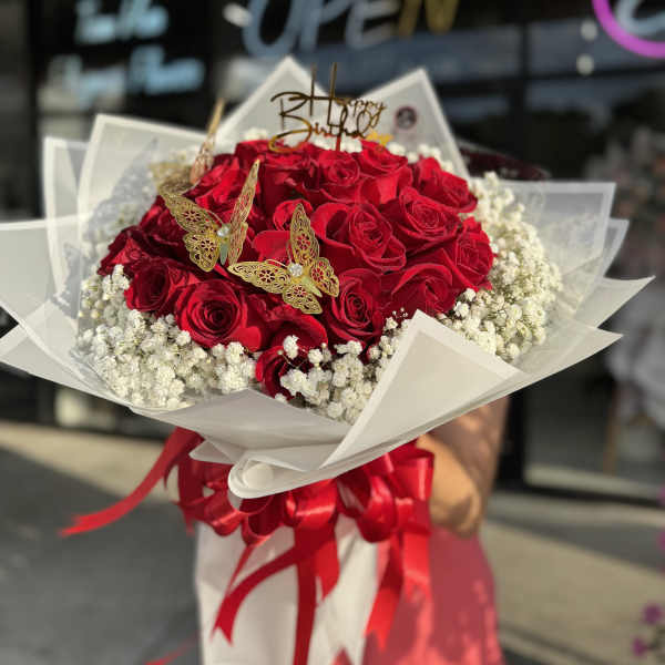 Red rose bouquet with baby’s breath, butterfly picks, and a birthday topper