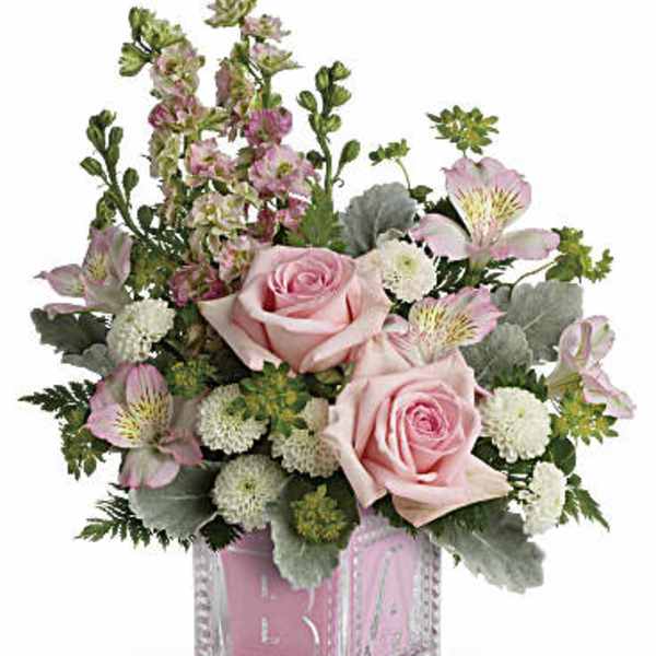 Pink roses and mixed flowers arranged in a clear glass cube vase