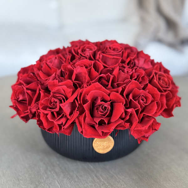 Round arrangement of red roses in a black vase