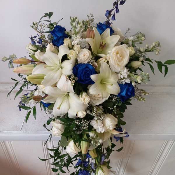 Cascade bouquet of white lilies, roses, and blue flowers