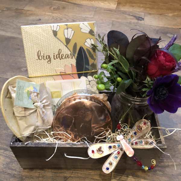 Gift basket with a small flower arrangement, candle, and stationery items