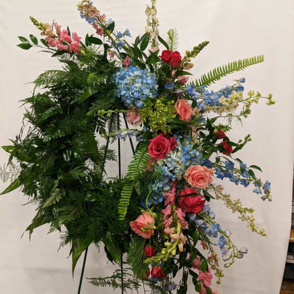 Large standing floral spray with roses, hydrangeas, and blue blossoms