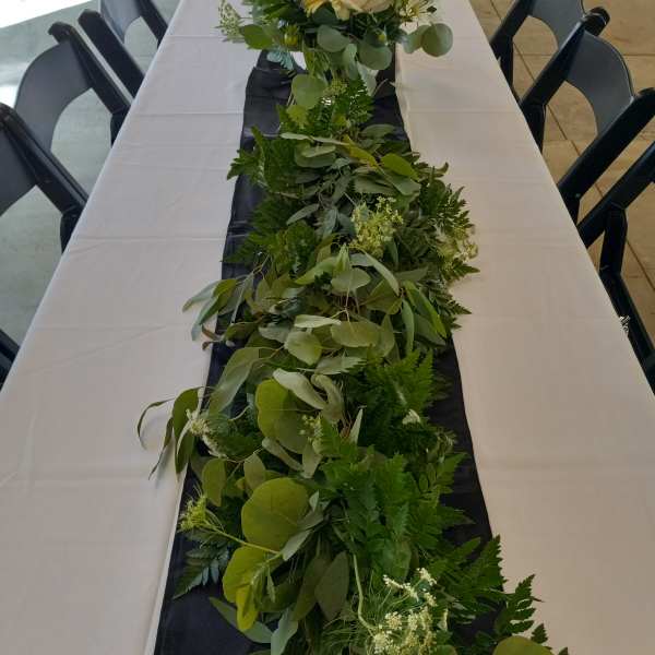 Long greenery garland with white roses on a banquet table