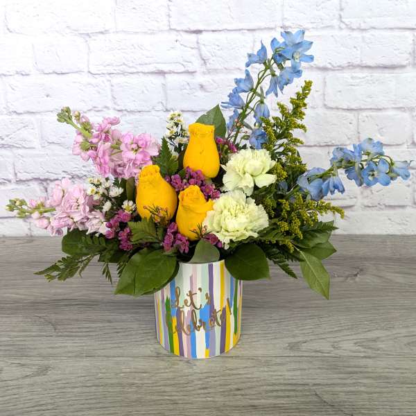 Colorful flower arrangement in a striped container with yellow roses