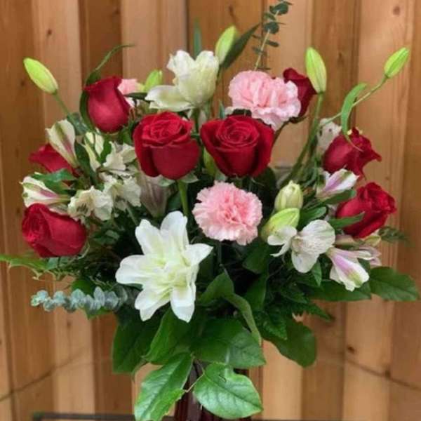 Bouquet of red roses, white lilies, and pink carnations in a red vase