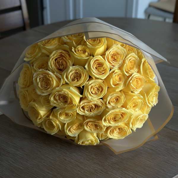 Bouquet of yellow roses wrapped in white paper